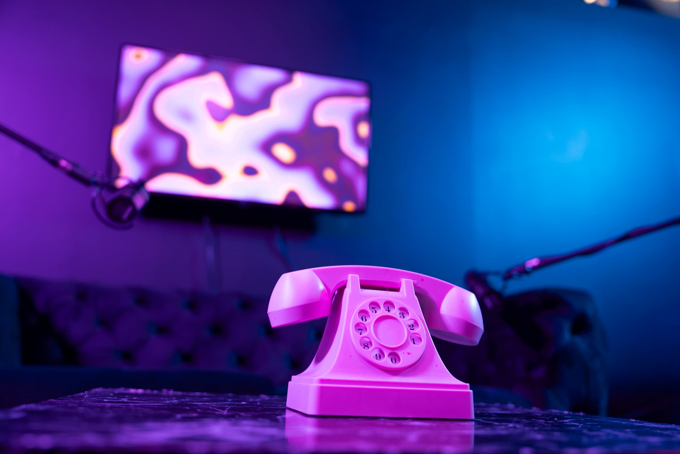 Podcast set at Lush Event Space — pink rotary phone, boom mics, liquid visuals on screen